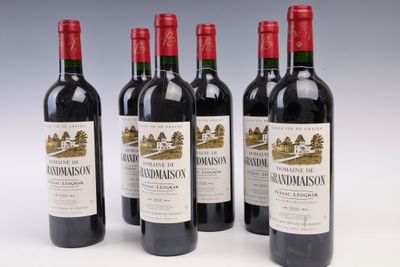 quatre bouteilles de vin rouge sont alignées sur une surface blanche