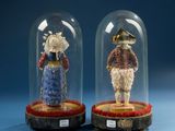two figurines of people under glass domes on a blue surface