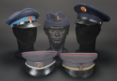 trois casquettes militaires sur une tête de mannequin, sur fond noir