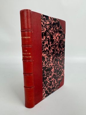 un livre rouge à la couverture noire et rouge posé sur une surface blanche