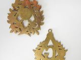 two brass medallions on a white surface with a white background