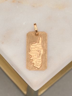 a gold pendant with a map on it on a marble table