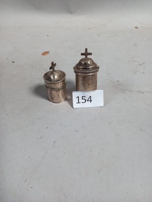 deux petits objets en argent posés sur une table, accompagnés d'une étiquette de prix