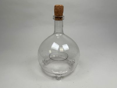 an empty glass bottle with a cork stopper sitting on a table