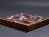 a small wooden plate with a gold ring on it