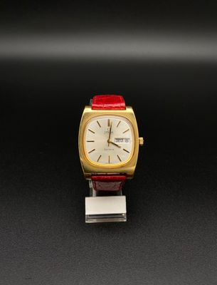 une image représentant une montre dorée et rouge posée sur un fond noir