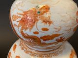 a white vase with orange designs on it sitting on a table