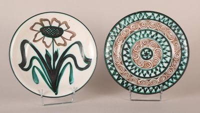 two decorative plates with designs on them sitting on a table