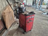 une boîte rouge posée dans un garage, à côté d'un tas de vieilleries