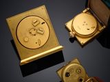 three gold - plated watches are sitting on a black surface with a black background