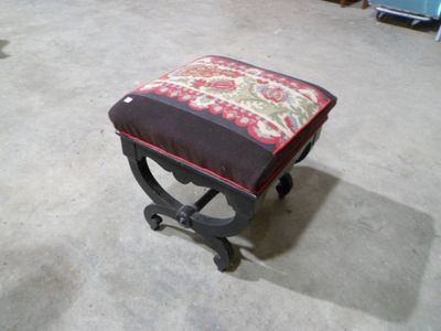 un petit tabouret recouvert d'un coussin rouge et vert
