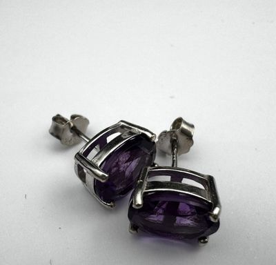 une paire de boucles d'oreilles en amethorate posées sur une surface blanche