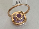 a close up of a ring with a purple stone on it