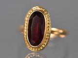 Gros plan sur une bague en or ornée d'une pierre rouge