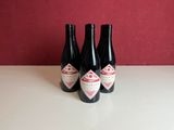 trois bouteilles de vin posées sur une table, avec un mur rouge en arrière-plan