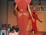a woman that is walking down the runway in a red dress