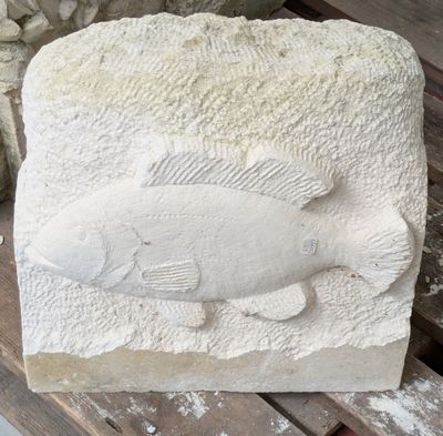 une sculpture en pierre représentant un poisson assis sur un banc