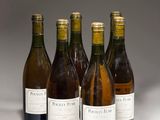 six bouteilles de vin sont alignées sur une surface blanche