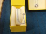 a yellow box with a necklace in it and a yellow box with a bracelet in it