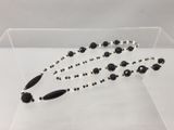 un collier de perles noires et blanches présenté dans une vitrine transparente