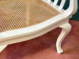 a white bench that has a wicker seat on it