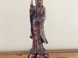 statue of a person sitting on a wooden table with a white wall in the background