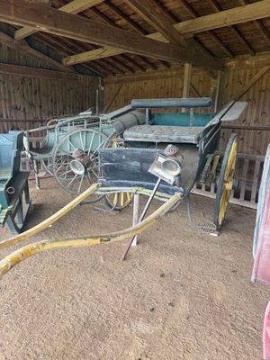 une calèche dans une grange, à laquelle est raccordé un tuyau d'arrosage