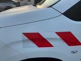 une camionnette blanche à rayures rouges garée sur un parking