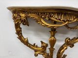 a gold table with a marble top on a white wall