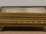 a small gold box with a mirror on top of it