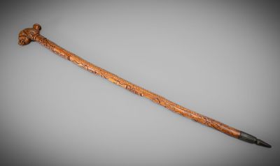 a close up of a cane with a wooden handle on a gray surface