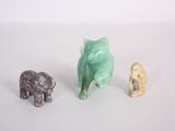 three small figurines of animals on a white surface
