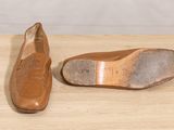 pair of brown leather shoes sitting on top of a wooden table