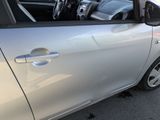 a silver car parked in a parking lot with a dog sitting in the passenger seat