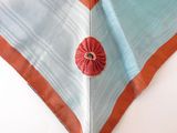 a close up of a blue and orange scarf with a flower on it