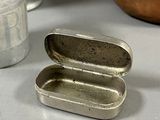 a small tin with a lid sitting on a table next to other tins
