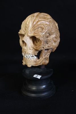 un crâne sculpté sur un socle noir, avec un fond noir