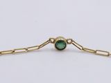 a close up of a gold bracelet with a green stone