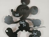 a mickey mouse clock on the wall with writing on it