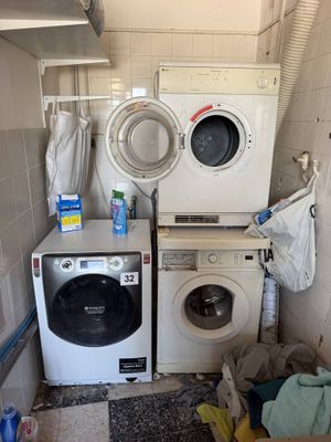 deux lave-linge et un sèche-linge dans une petite pièce