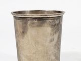 an old silver cup sitting on top of a white surface