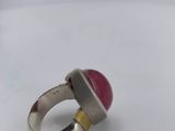a close up of a ring with a red stone on it