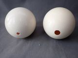 two white balls with holes on them sitting on a table
