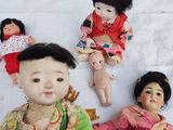 five dolls of asian children sitting on a blanket