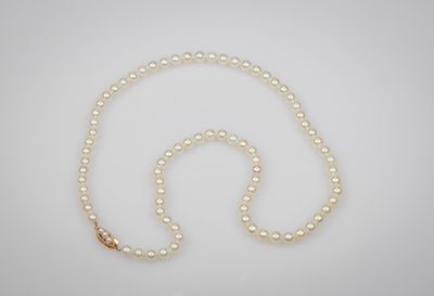 un collier de perles blanches avec un fermoir en or sur fond blanc