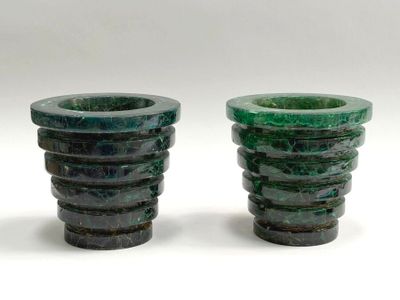 pair of green glass vases sitting on top of a white surface