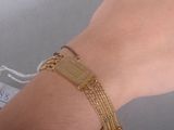 la main d'une femme portant un bracelet en or et une médaille