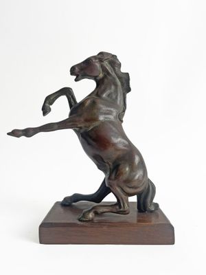 statue of a horse standing on its hind legs on a wooden base
