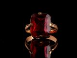 un gros plan d'une bague ornée d'une pierre rouge sur un fond noir