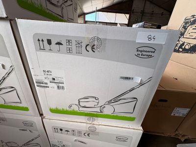 des cartons contenant des tondeuses à gazon empilés les uns sur les autres dans un entrepôt